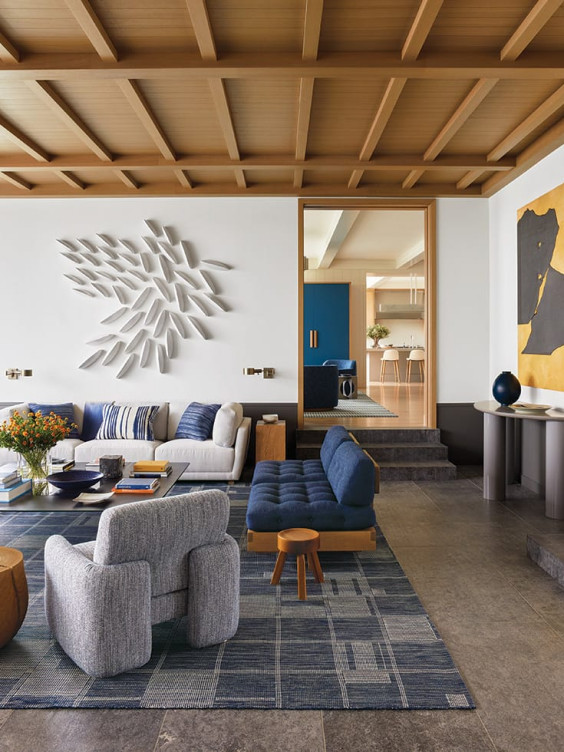 Modern living room with blue and gray furniture, wall art, and wooden ceiling, showcasing a contemporary interior design.