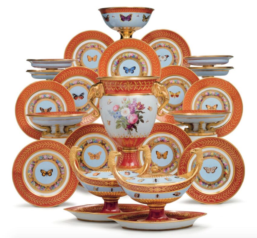 A pyramid of ornate porcelain dinnerware with butterfly motifs and golden accents arranged on a white background.