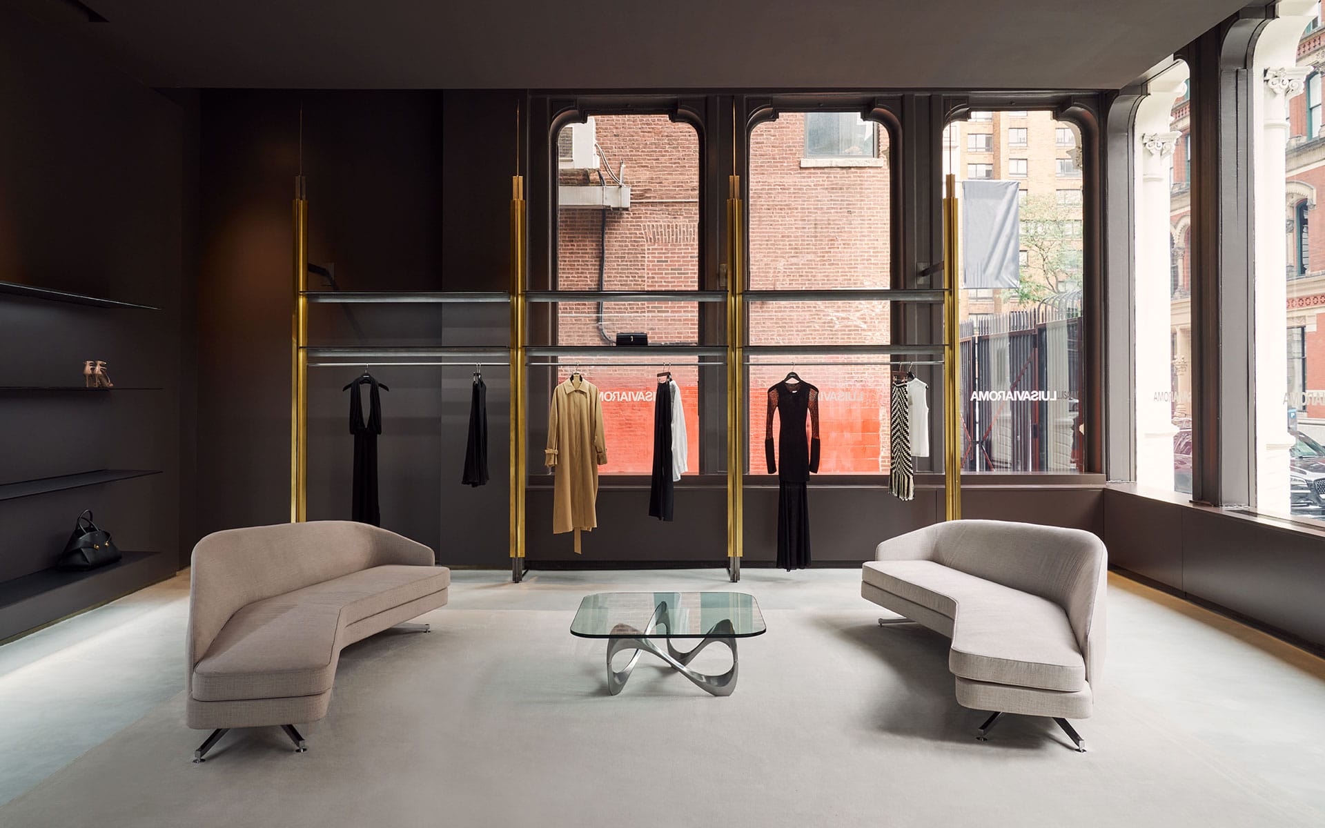 Inside of store with seating area in front of clothes.