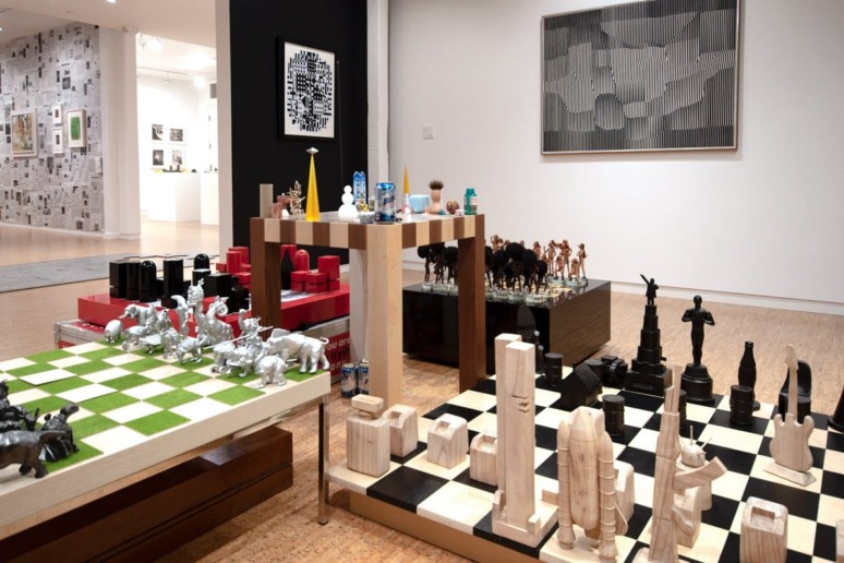 Art gallery display featuring diverse chess sets, including animal and sculpture-themed pieces on checkered boards.