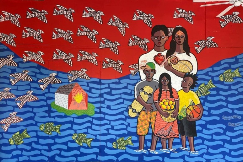 Colorful mural depicting five people with fruit and fish, standing in water with flying fish and a house in the background.