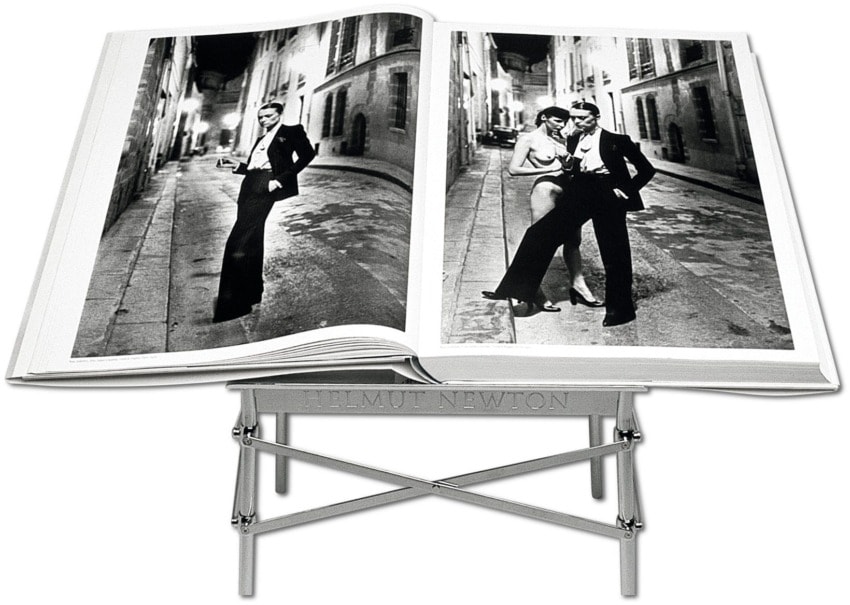 Open luxury coffee table book showcasing black and white fashion photography on a stylish stand.