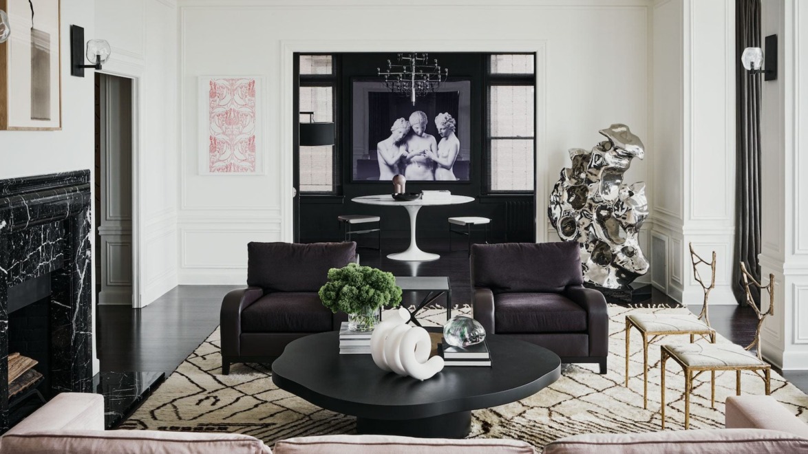 Modern living room with dark furniture, abstract art, round table, and decorative sculptures.