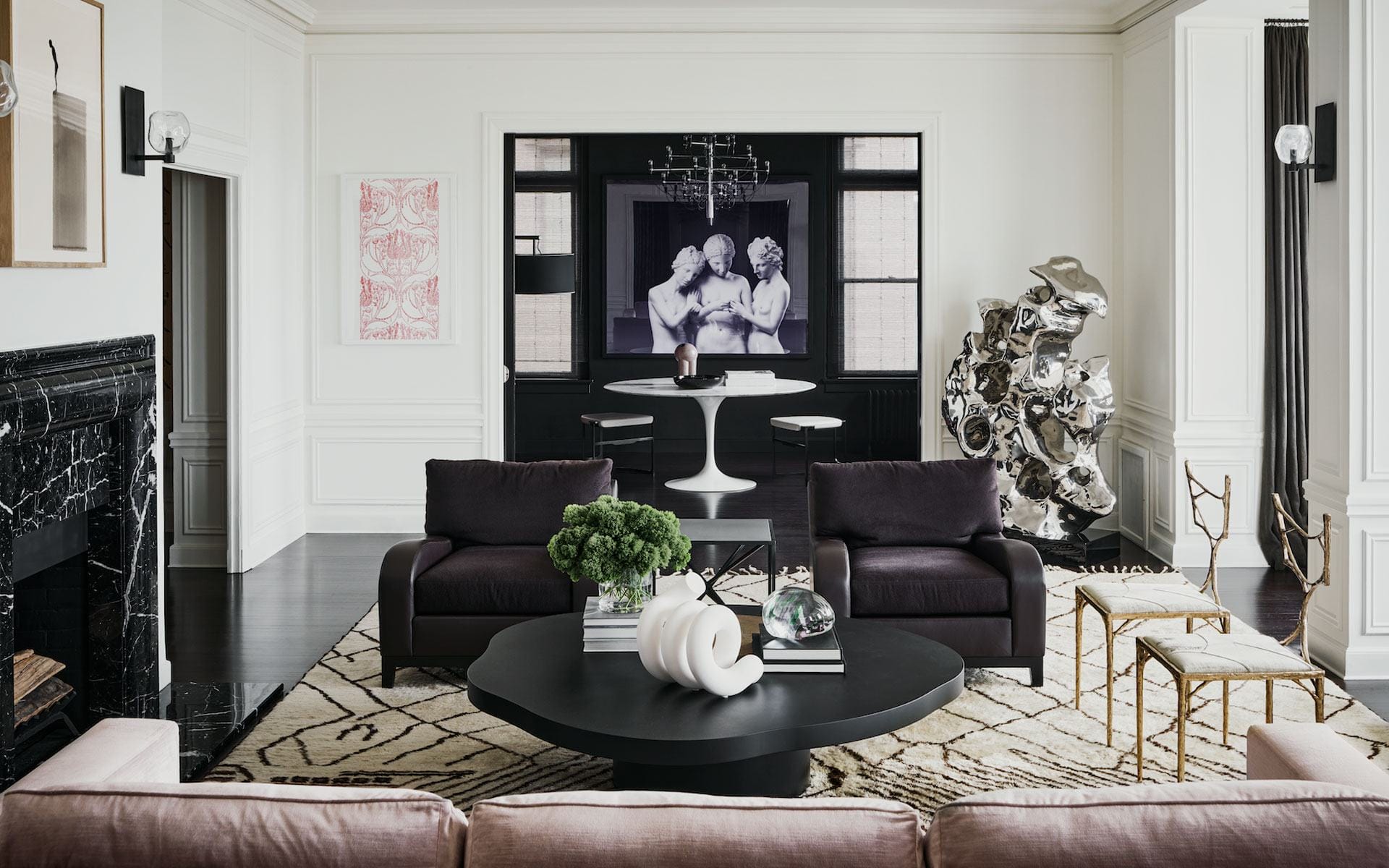 Modern living room with dark furniture, abstract art, round table, and decorative sculptures.