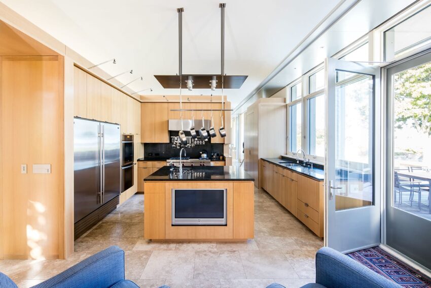 Modern kitchen with wooden cabinets, stainless steel appliances, center island, and large windows with outdoor view.