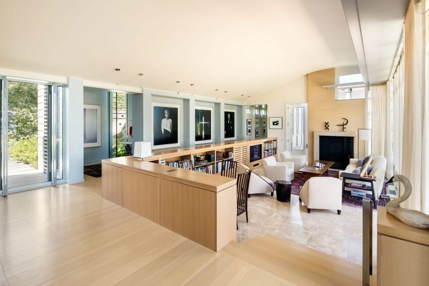 Spacious modern living room with light wood flooring, art on walls, white sofas, and large windows.