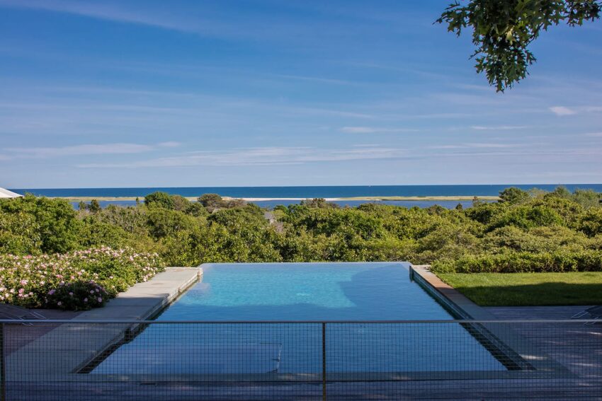 Infinity pool overlooking a lush landscape with the ocean in the background under a clear blue sky