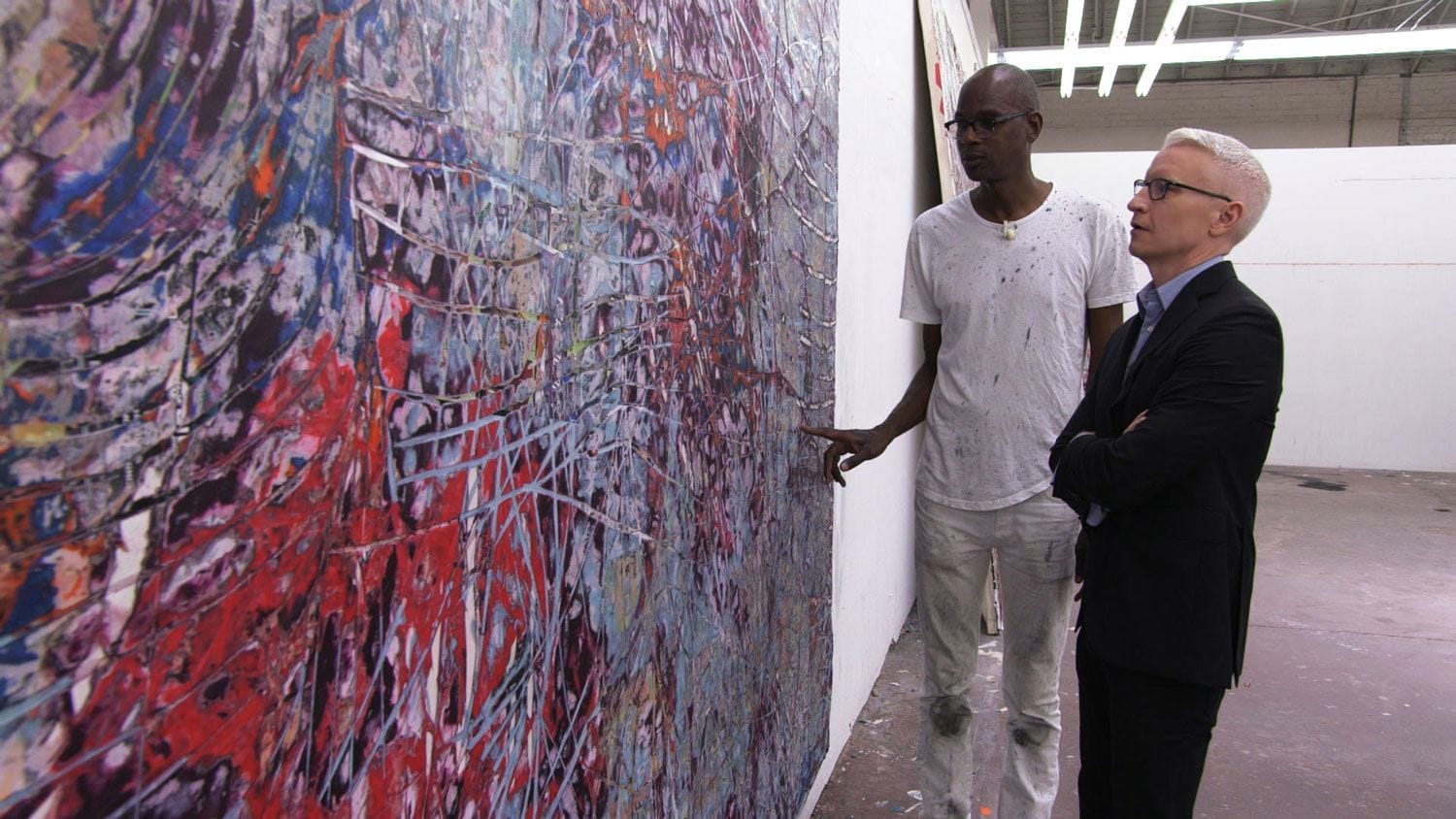 Two people discussing an abstract painting in an art gallery.