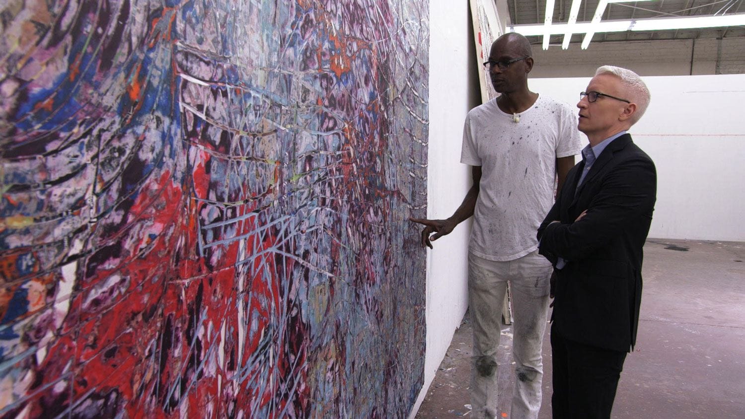 Two people discussing an abstract painting in an art gallery.