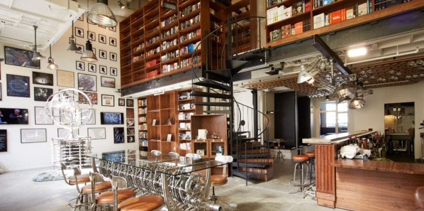 Modern loft with spiral staircase, bookshelves, glass dining table, and industrial-style decor.