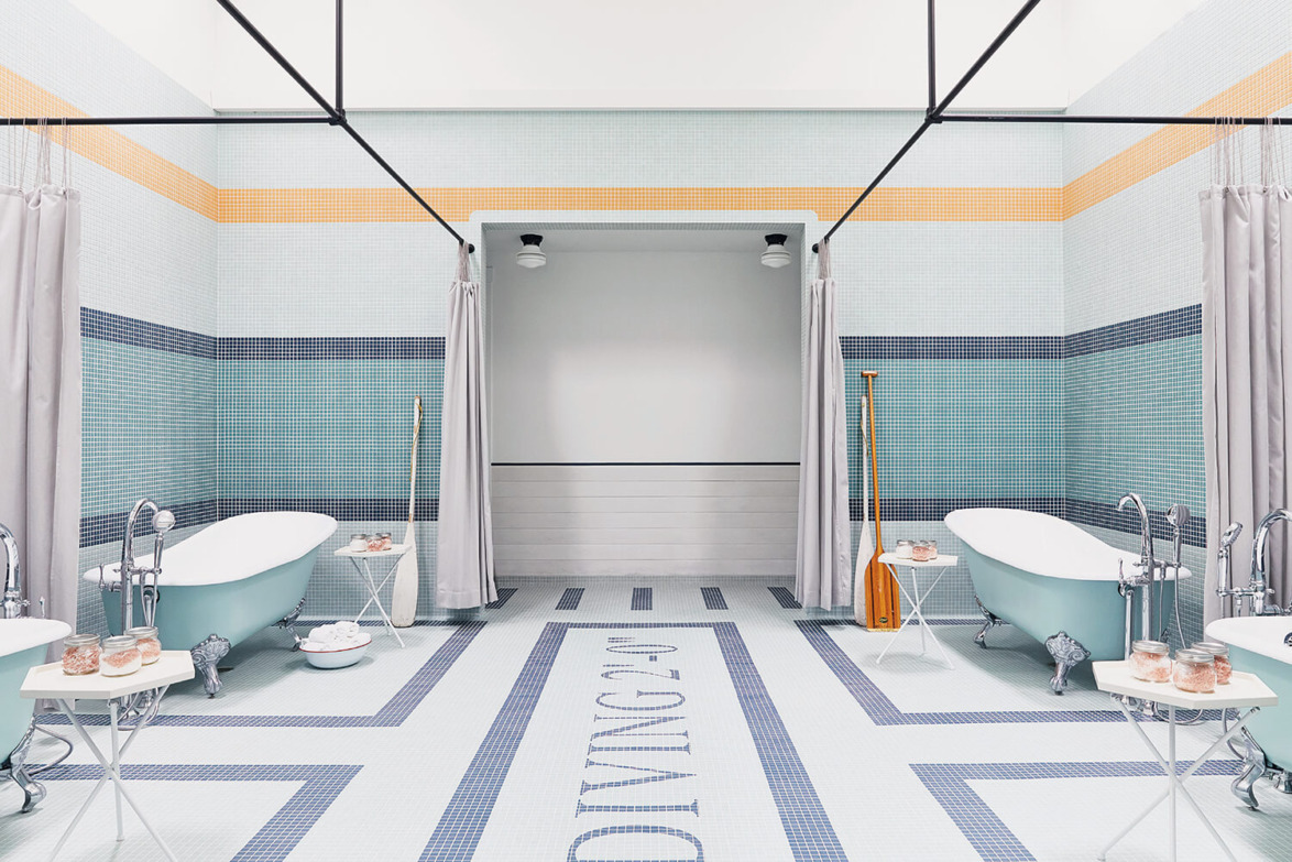 Elegant bathroom with two vintage-style bathtubs, pastel tiles, curtains, and a wooden paddle for decoration.