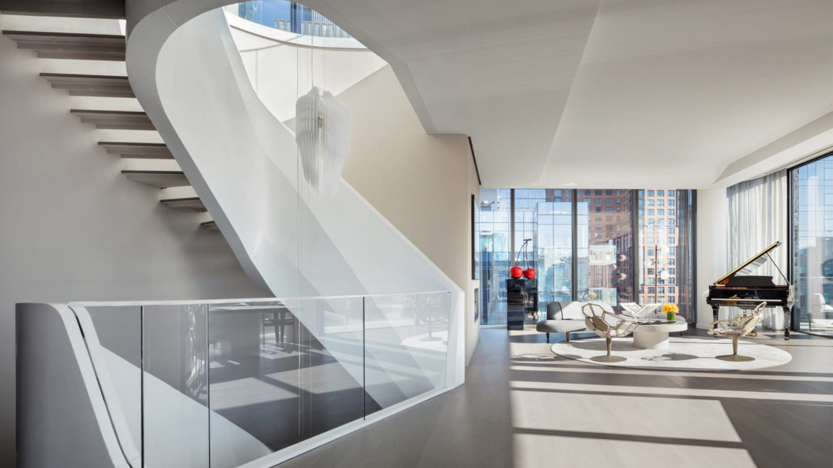 Modern living room with a sleek spiral staircase, large windows, seating area, and grand piano, flooded with natural light.