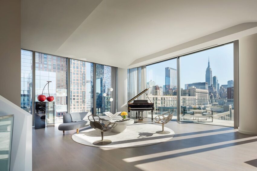 Modern living room with a grand piano, city skyline view, and elegant furniture in a high-rise apartment with large windows.