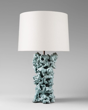 Unique table lamp with a textured turquoise base and a large white shade against a neutral background