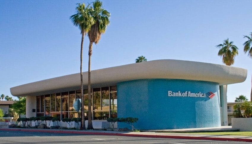 Bank of America building with a modern design and palm trees, set against a clear blue sky.