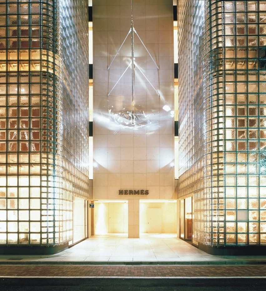 Storefront of a luxury brand with illuminated glass block exterior, elegant entrance, and brand name above the door.
