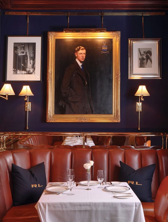 Luxurious restaurant booth with leather seating, table set elegantly, and framed portraits on the dark-paneled wall.