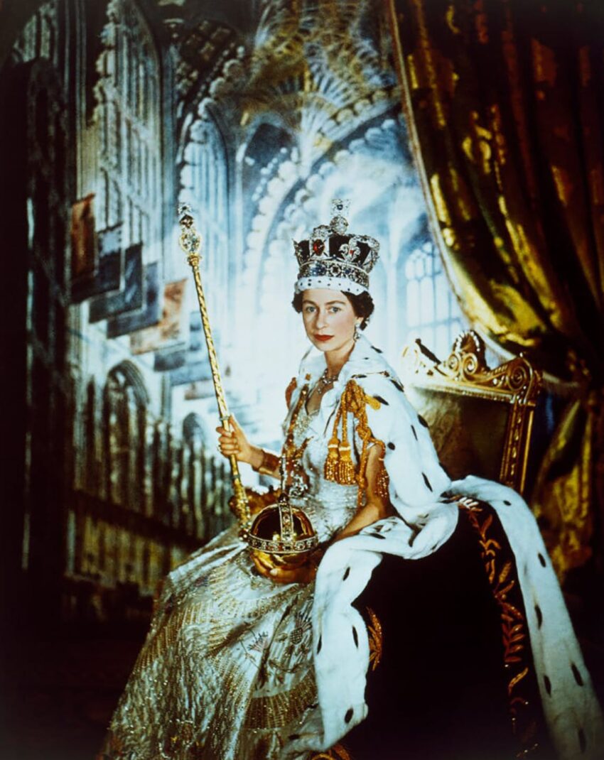 A royal figure seated on an ornate throne, wearing a crown and holding a scepter, in a richly decorated palace interior.