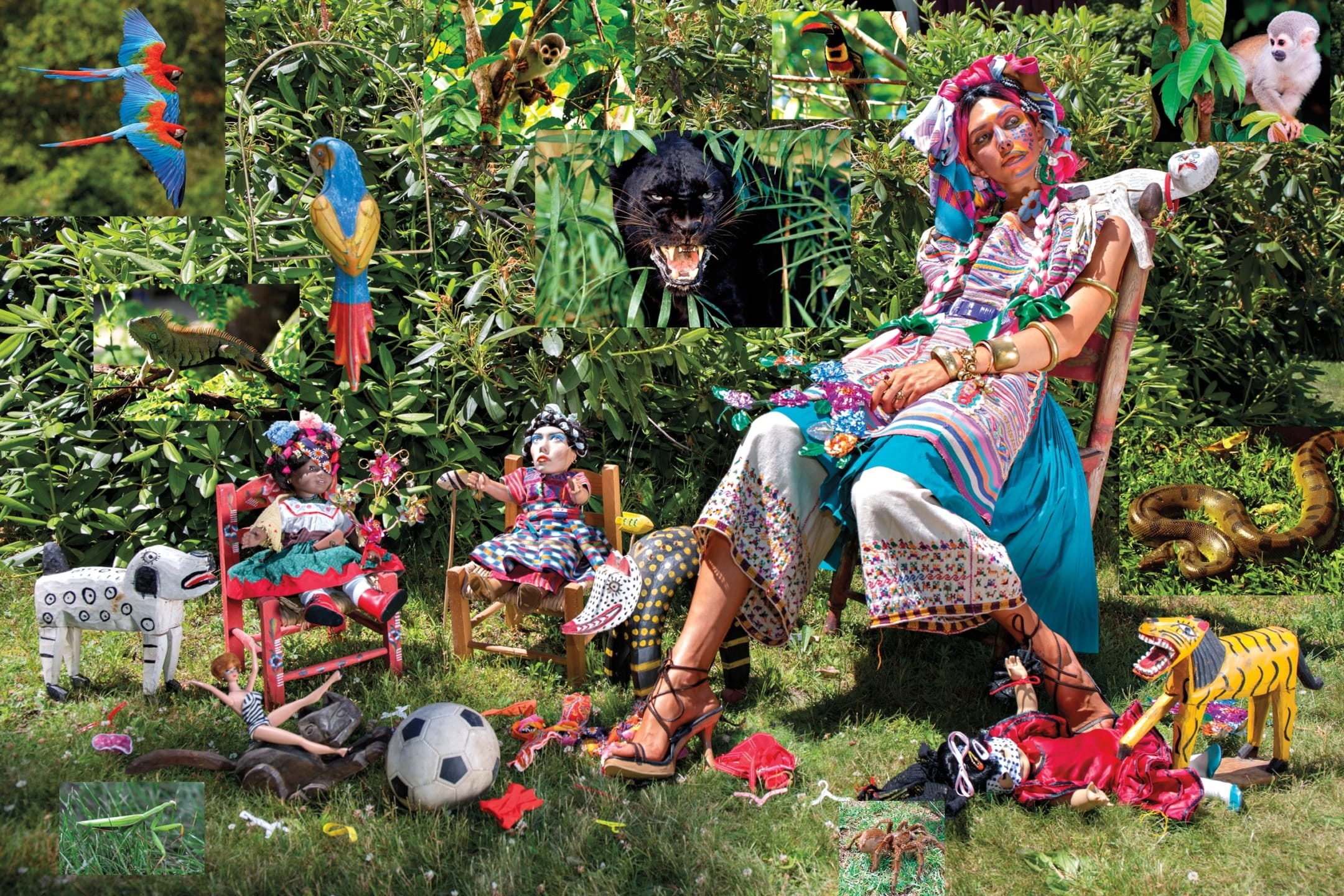 Woman in colorful attire seated outdoors surrounded by dolls, plants, and various animals including parrots and a leopard.