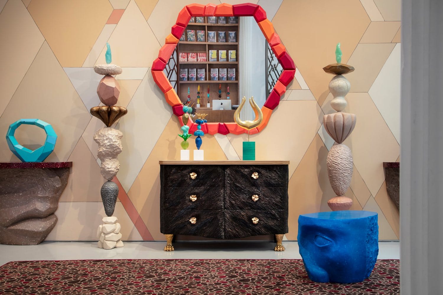 Colorful, eclectic room with geometric patterns, sculptures, a mirrored dresser, and vibrant decorations.