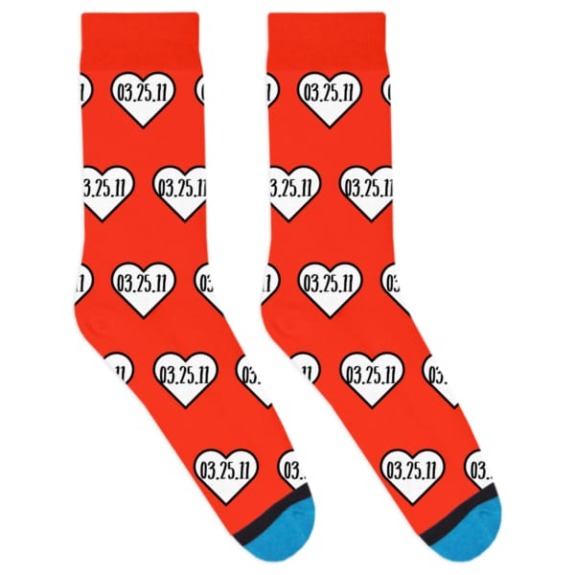 Red socks with white heart patterns, each displaying the date 03.25.11, blue toe caps.