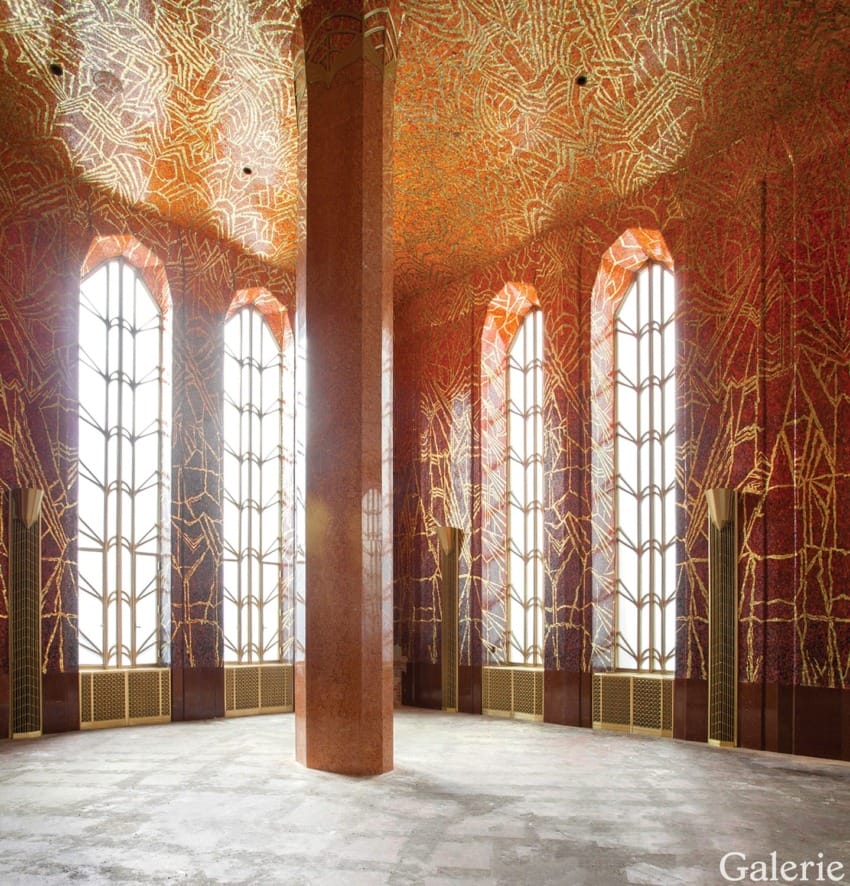 Room with tall arched windows, a central pillar, and intricate red and gold mosaic patterns on the walls and ceiling.