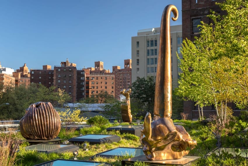 Bronze sculptures on a rooftop garden with urban buildings in the background under a clear blue sky.