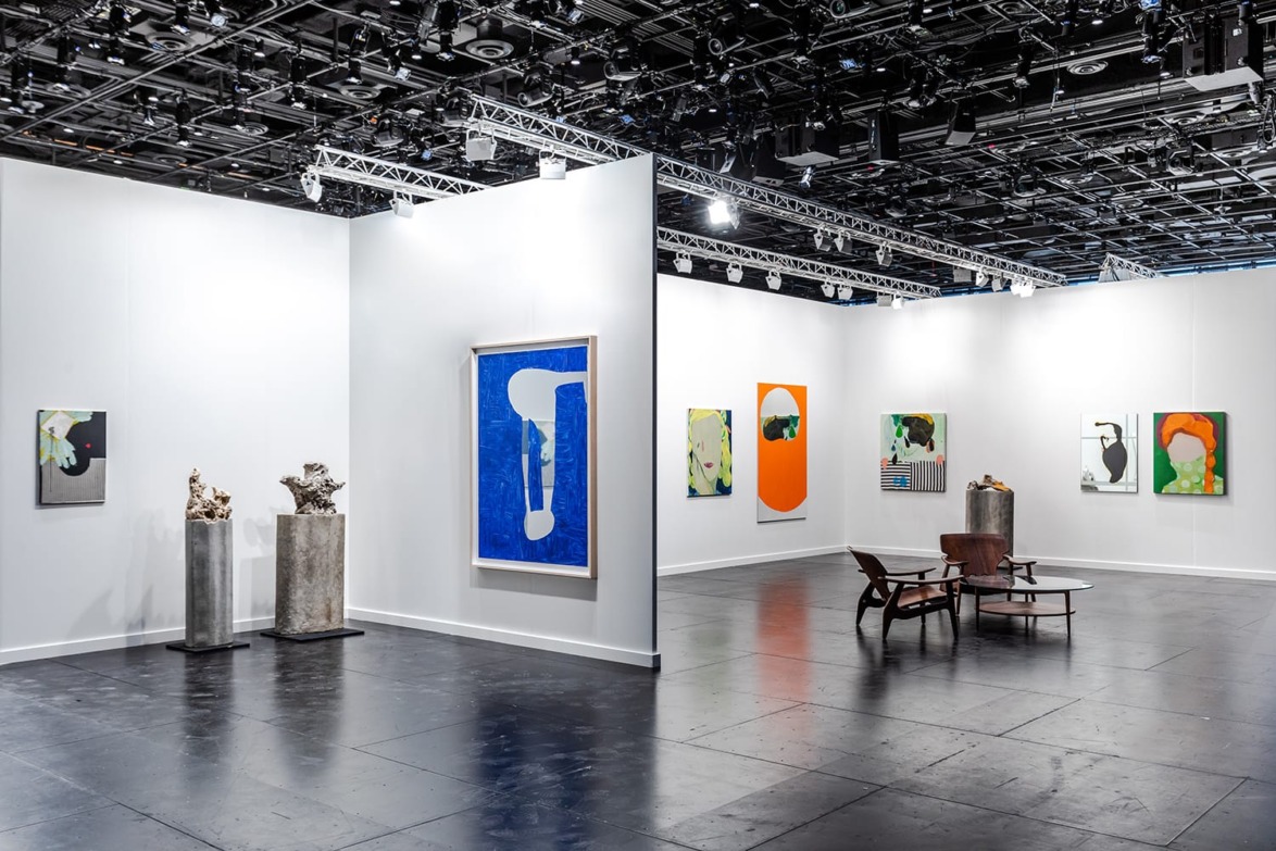 Art gallery exhibition with abstract paintings on white walls and sculptures on metal pedestals, modern interior design.