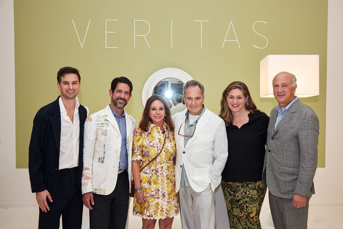 Group of six people standing in front of a green wall with "VERITAS" text.