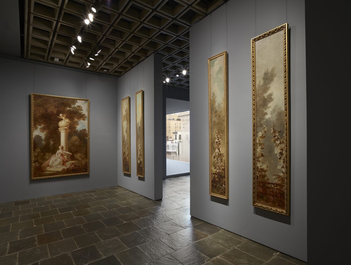 art gallery interior with framed paintings on gray walls and stone tile flooring