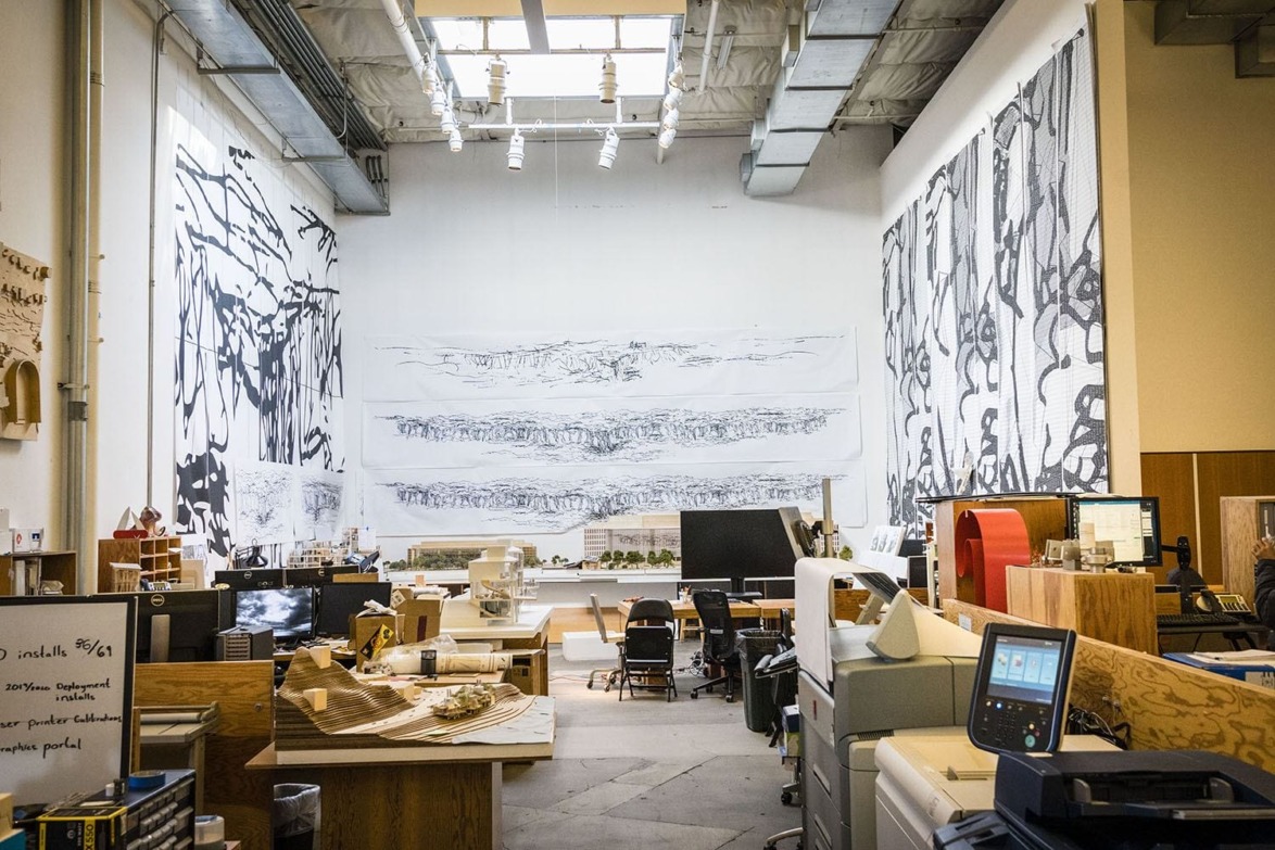 Spacious art studio with large black and white wall murals, various art supplies, and workspace stations scattered throughout.