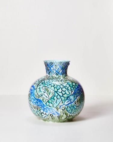 Ceramic vase with intricate blue and green fish and wave designs against a plain white background