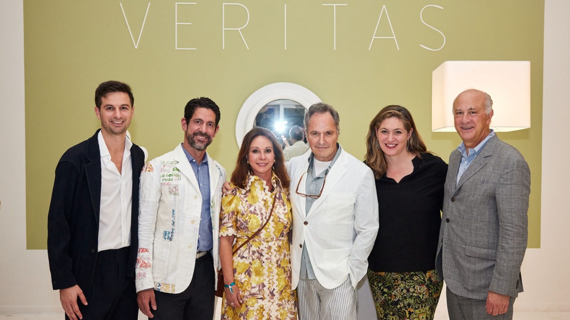Group of six people posing in front of a green wall with the word "VERITAS" displayed above.