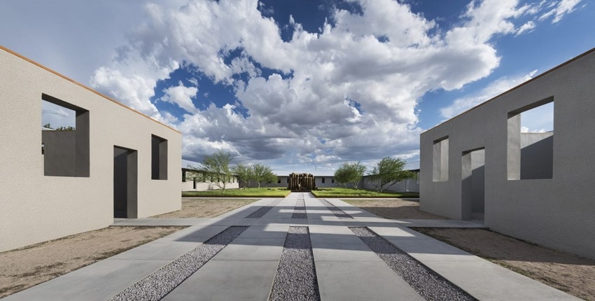 Modern architectural scene with minimalist concrete buildings, patterned walkway, lush greenery, and a dramatic cloudy sky.