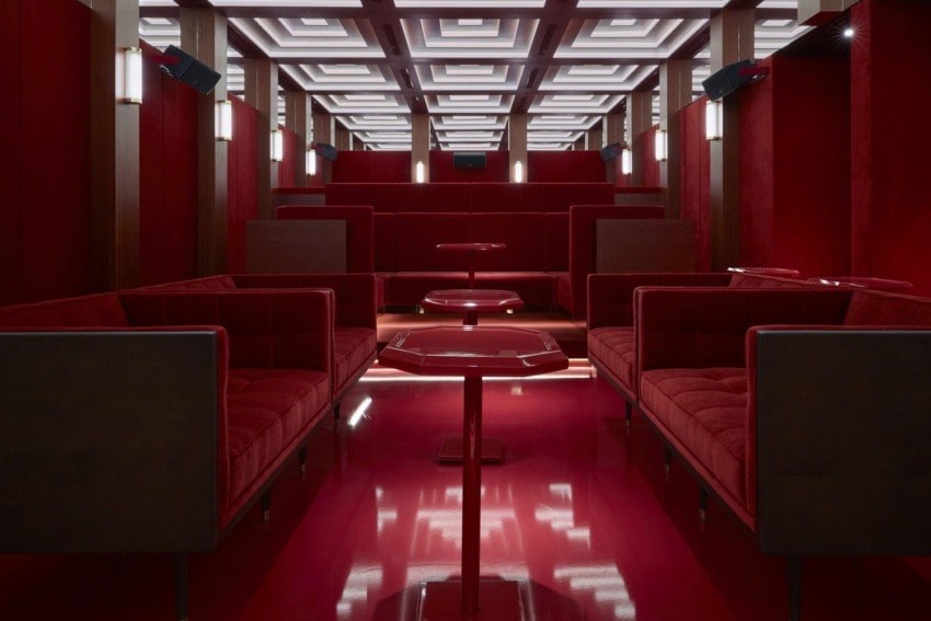 Luxurious red velvet seating arrangement in a modern, dimly-lit room with geometric ceiling design and ambient lighting.