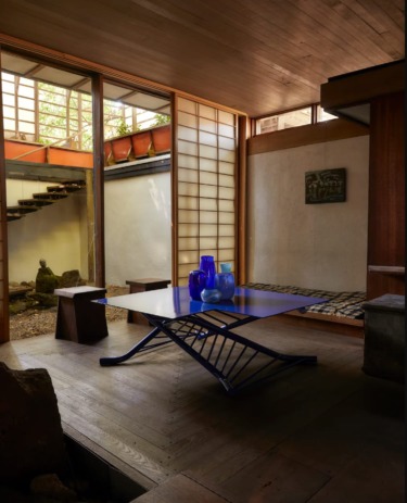 Minimalist Japanese-style room with wooden accents, large windows, and a blue glass centerpiece on a modern table.