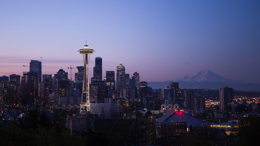 Seattle skyline at dusk with Space Needle and Mount Rainier in the background.