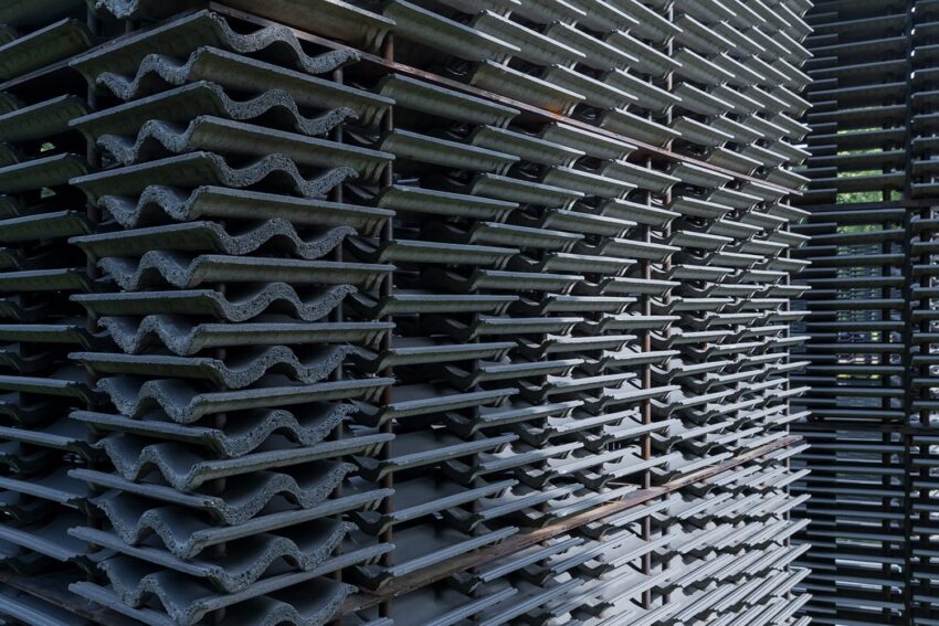 Stacks of corrugated metal sheets arranged in an intricate, layered pattern creating an industrial architectural effect.