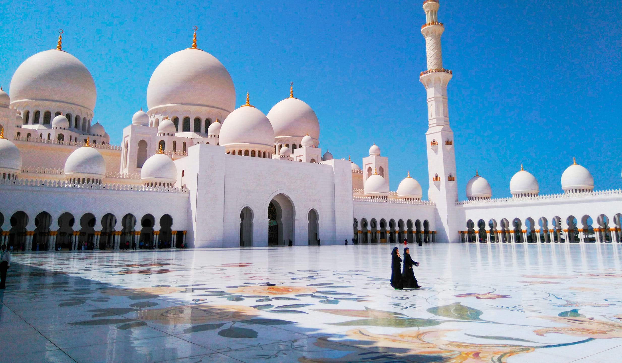 Sheikh Zayed Grand Mosque with clear blue sky and intricate courtyard design in Abu Dhabi, United Arab Emirates.