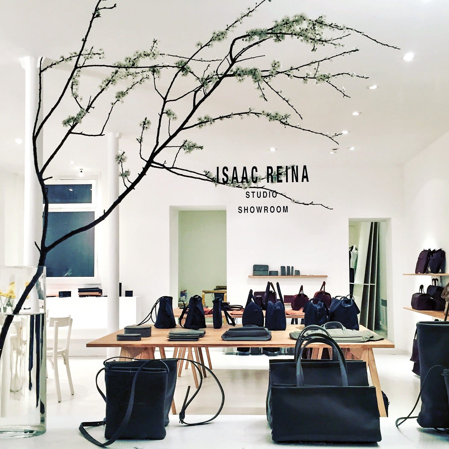 Chic showroom with modern decor, showcasing elegant bags and accessories on wooden tables, highlighting minimalistic design.