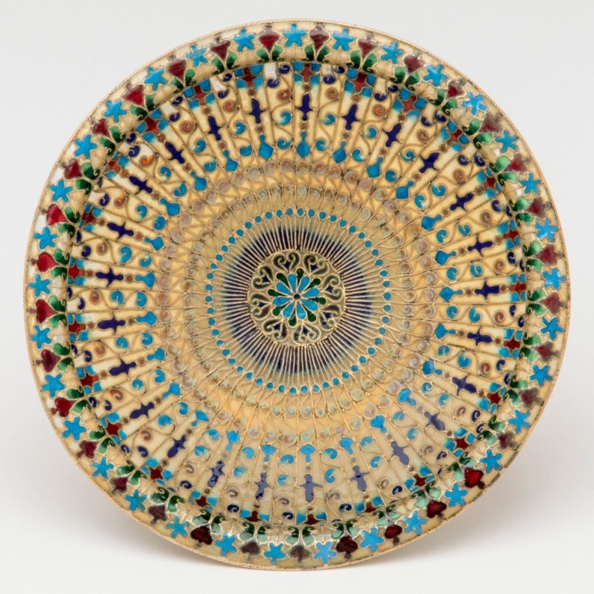 Intricate decorative ceramic plate with colorful geometric and floral patterns in blue, red, and gold.