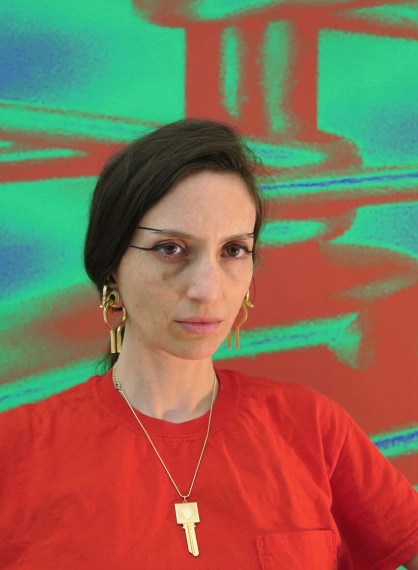 Person wearing a red shirt and gold jewelry stands against a vibrant red and green abstract background.