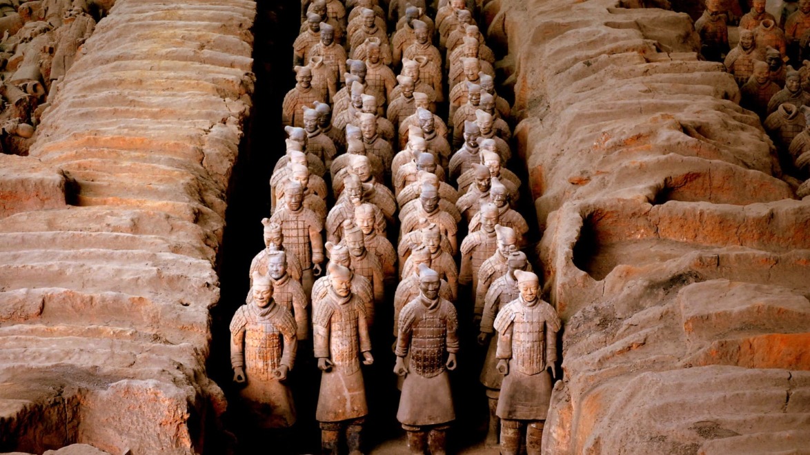 Terracotta Army soldiers standing in rows inside an archaeological excavation site in Xi'an, China.