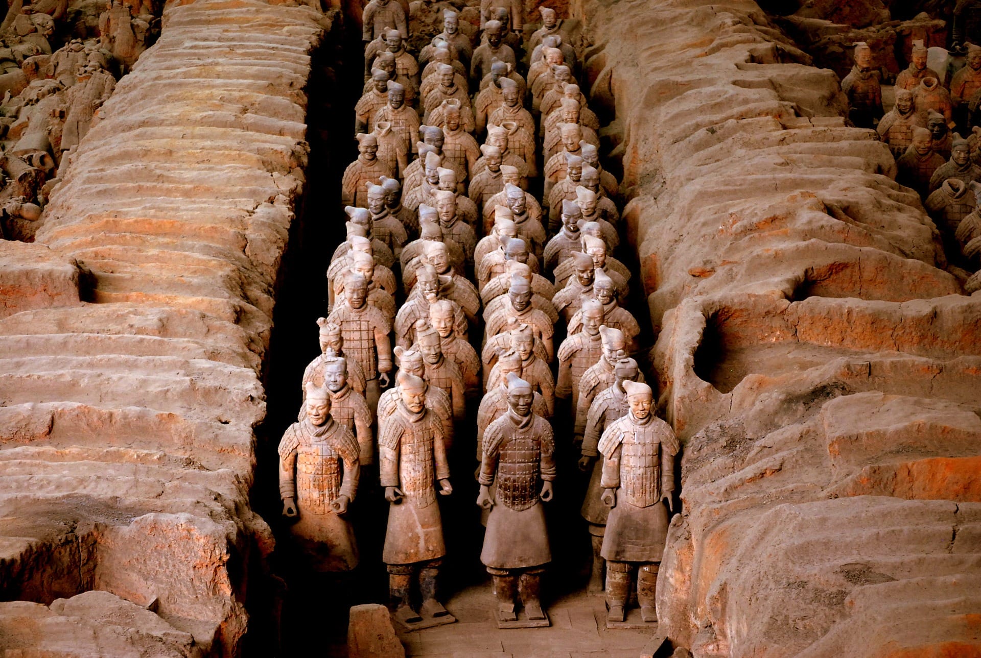 Terracotta Army soldiers standing in rows inside an archaeological excavation site in Xi'an, China.