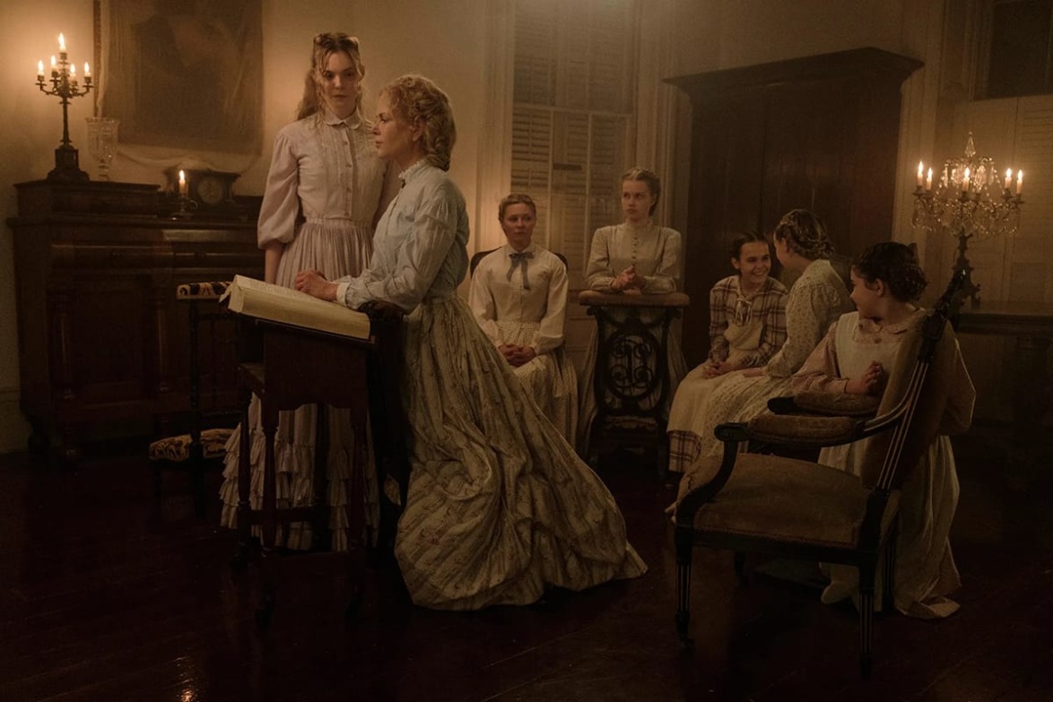 Victorian-era women gathered in a dimly lit room with candles and a wooden desk.