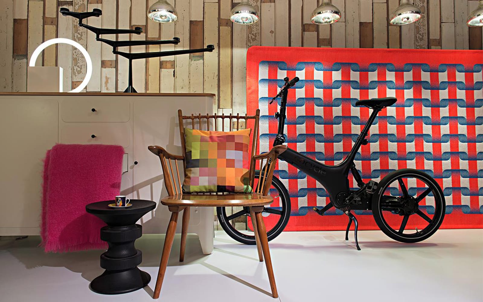 Modern room with unique bicycle, colorful checkered pillow on a wooden chair, vibrant rug, and stylish decor.