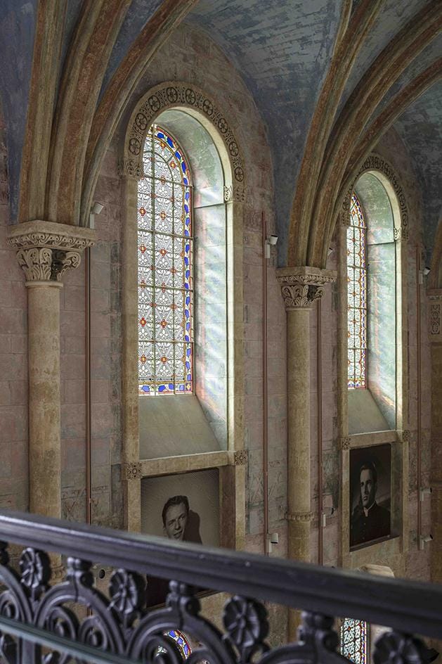 Gothic-style church interior with stained glass windows casting colorful light on stone walls and archways