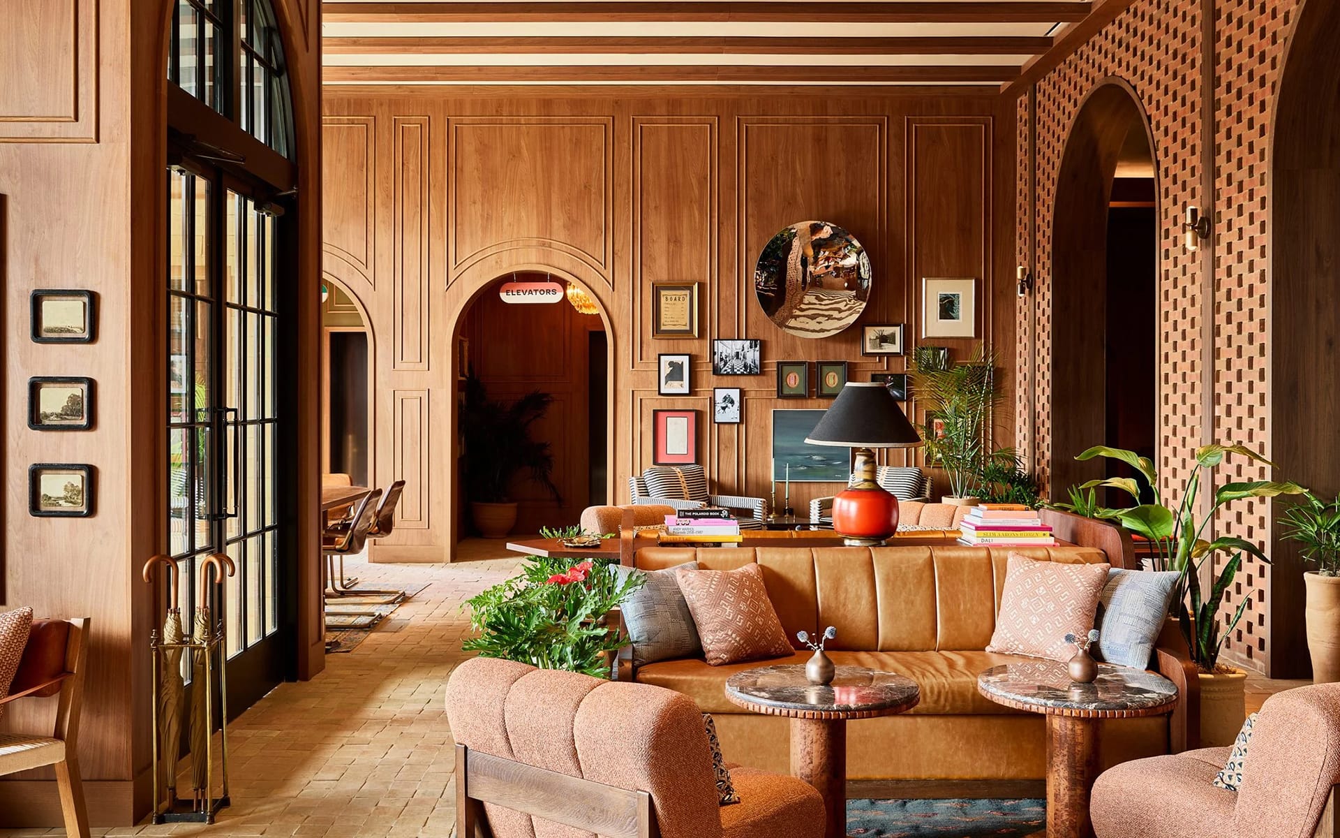 Cozy living room with wooden walls, leather couches, decorative plants, and framed art. Warm, inviting atmosphere.
