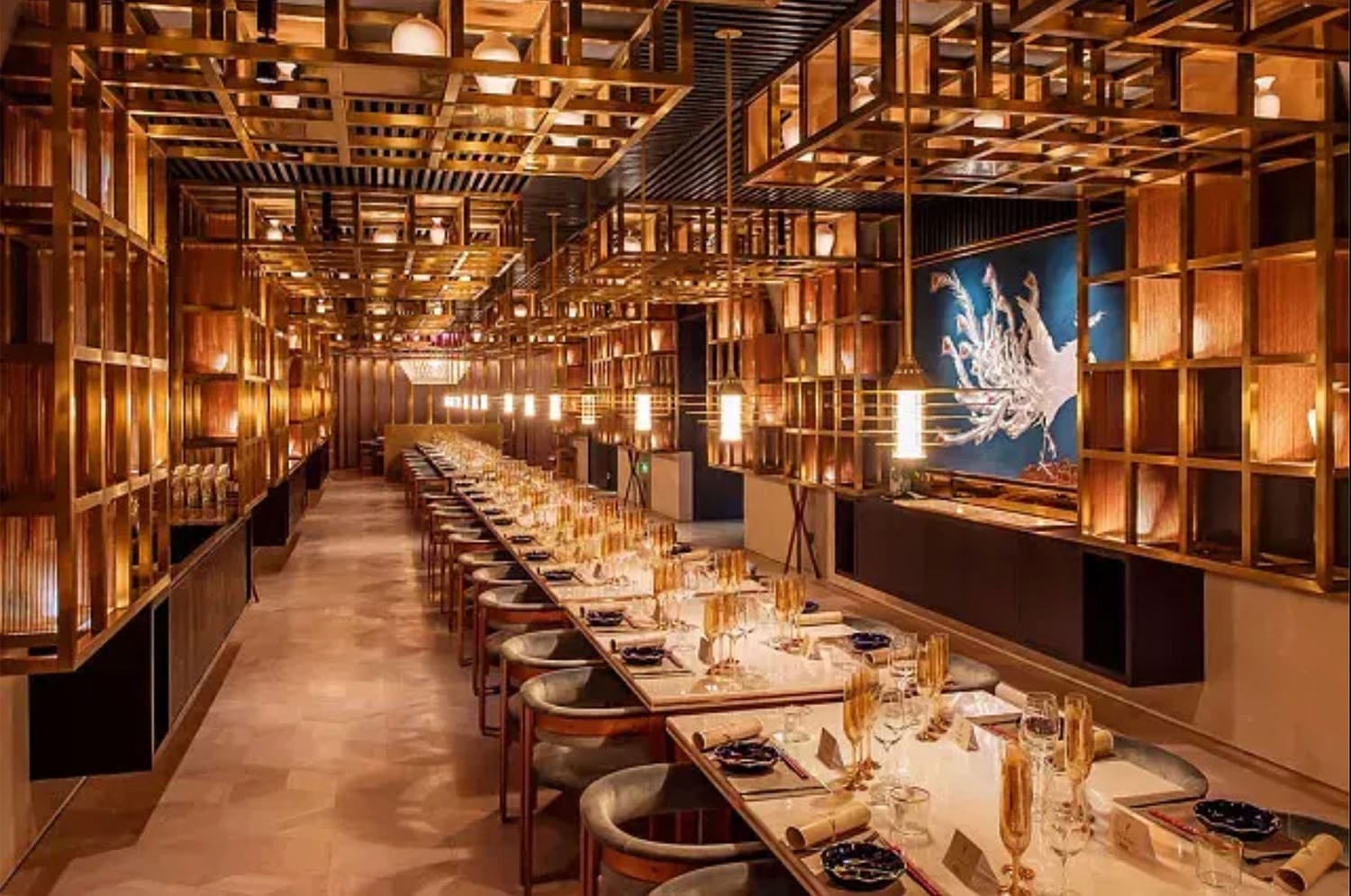 Elegant restaurant interior with long, beautifully set dining table, warm lighting, and artistic wooden lattice ceiling design.