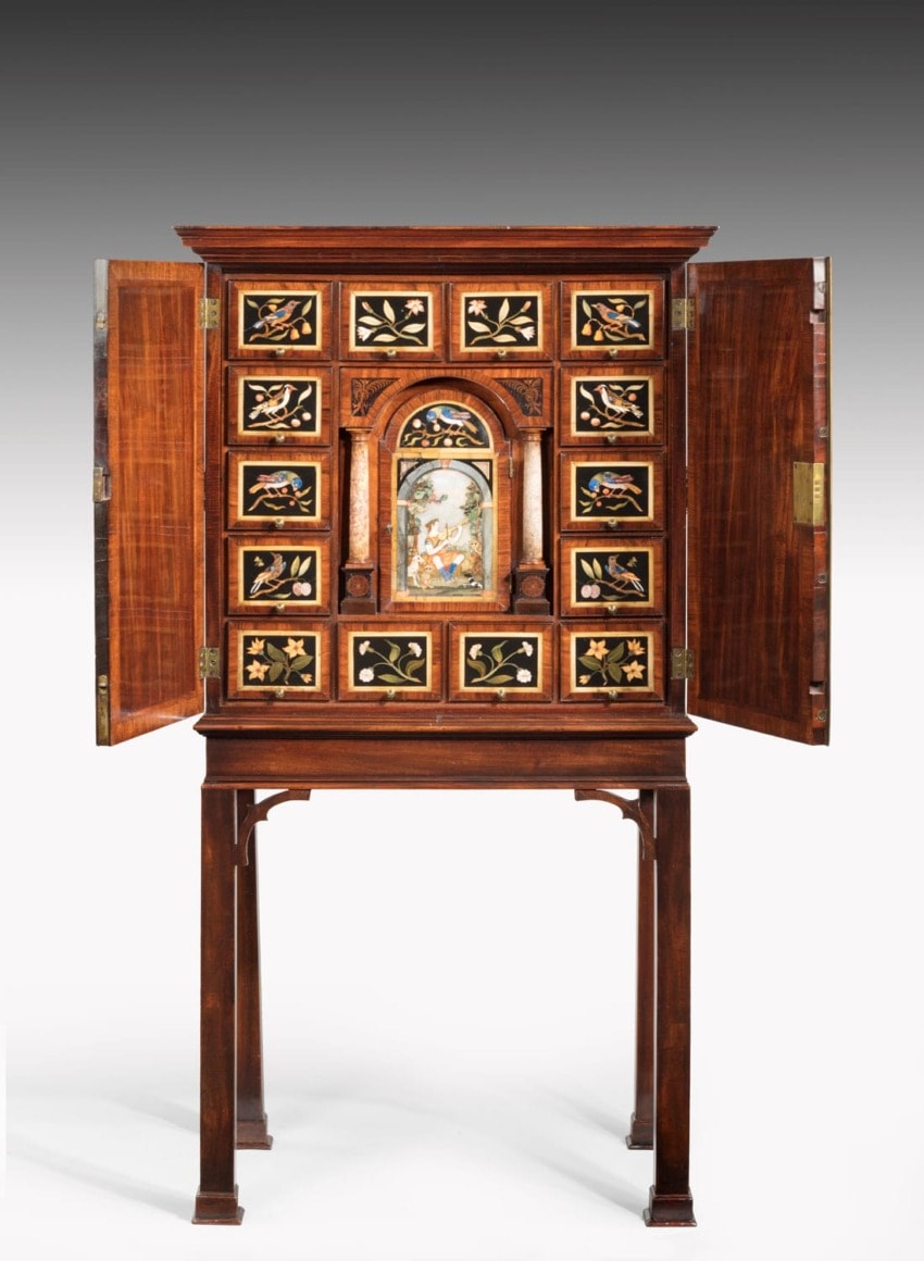 Antique cabinet with intricate inlay designs and open doors on a wooden stand.